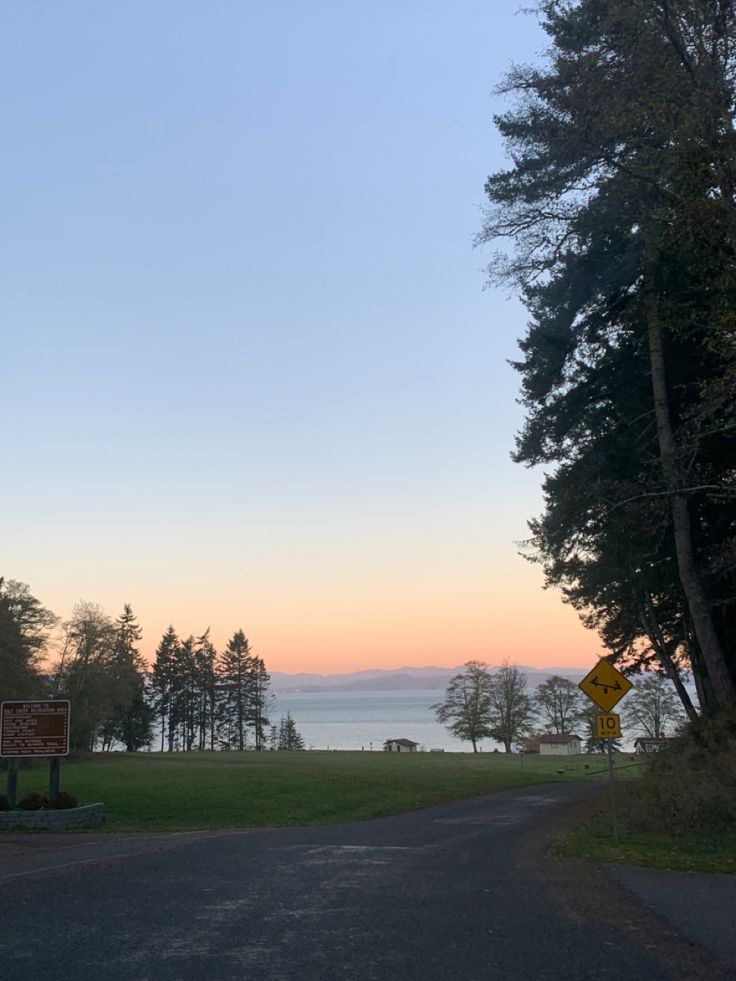 an empty road near the water at sunset