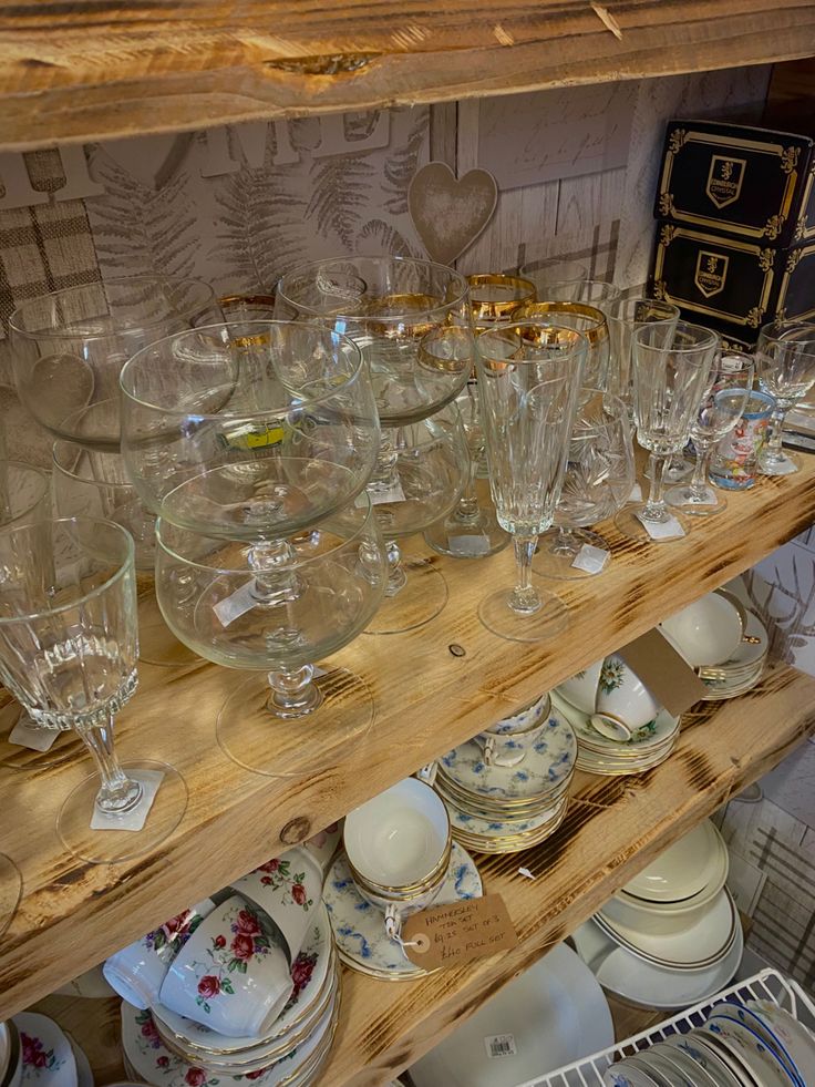 a shelf filled with lots of glassware and plates on top of wooden shelves next to a wall