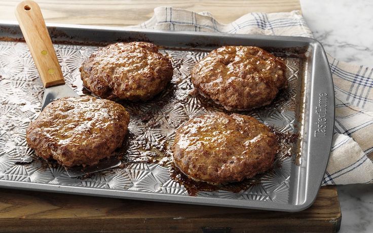 four hamburger patties sitting on top of a metal pan