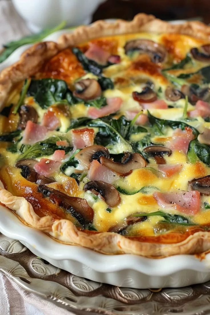 a quiche with spinach, ham and cheese in a pie pan on a table