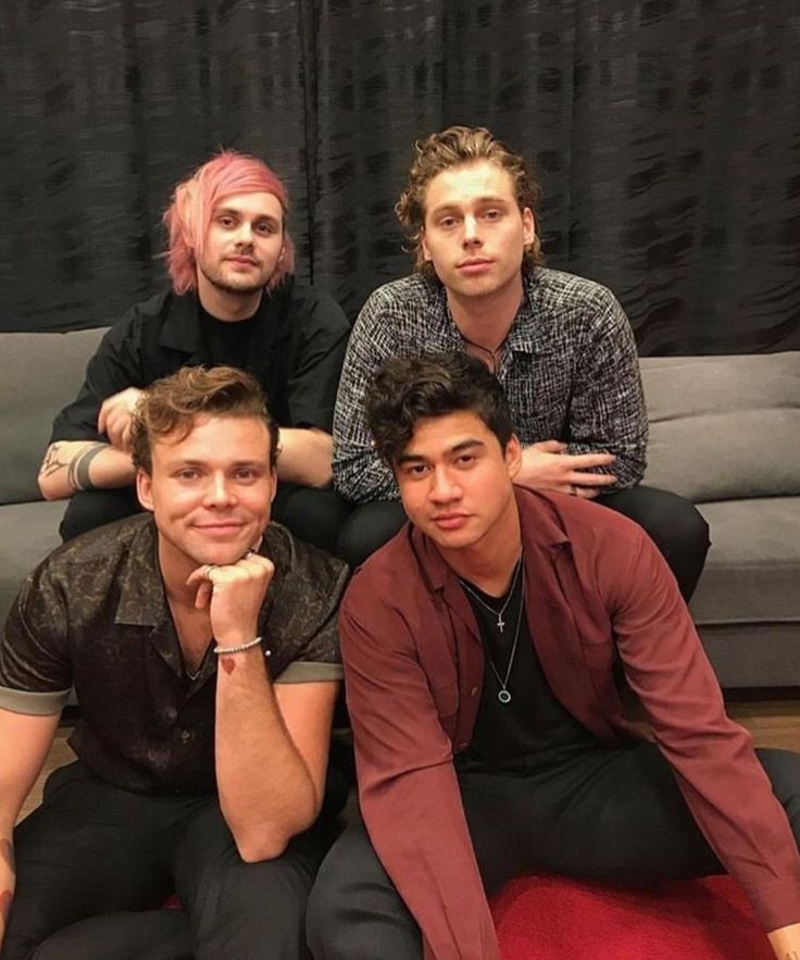 four young men posing for a photo in front of a couch