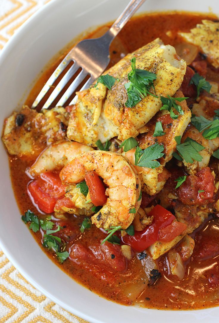 a white bowl filled with shrimp and tomato soup