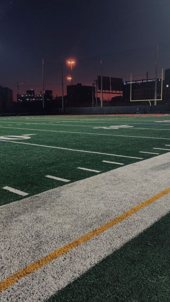 an empty football field at night with the lights on