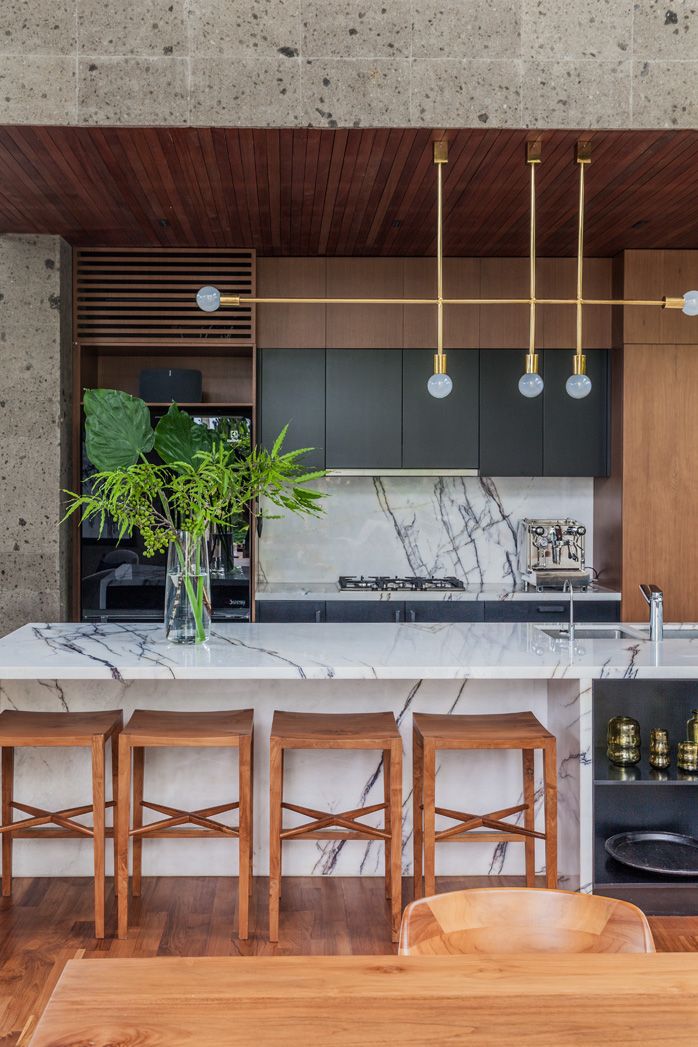 a kitchen with marble counter tops and wooden stools next to a dining room table