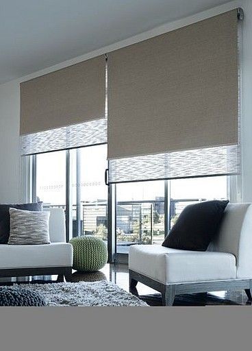 a living room with two white couches and brown shades on the windowsills