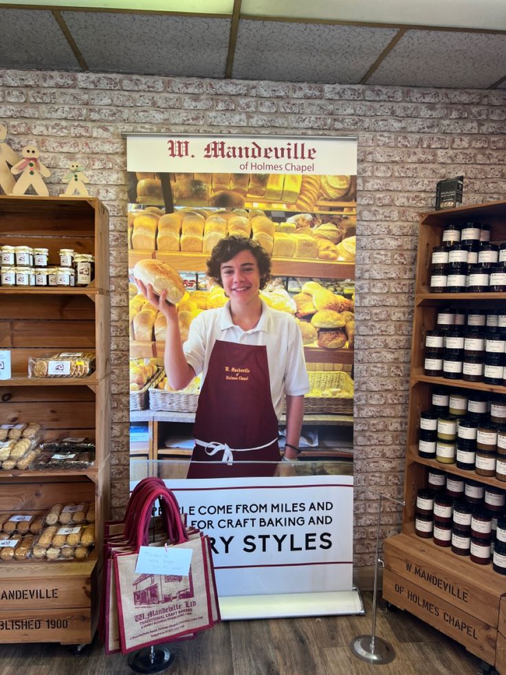 a man standing in front of a display of baked goods at a bakery with an advertisement on the wall behind him