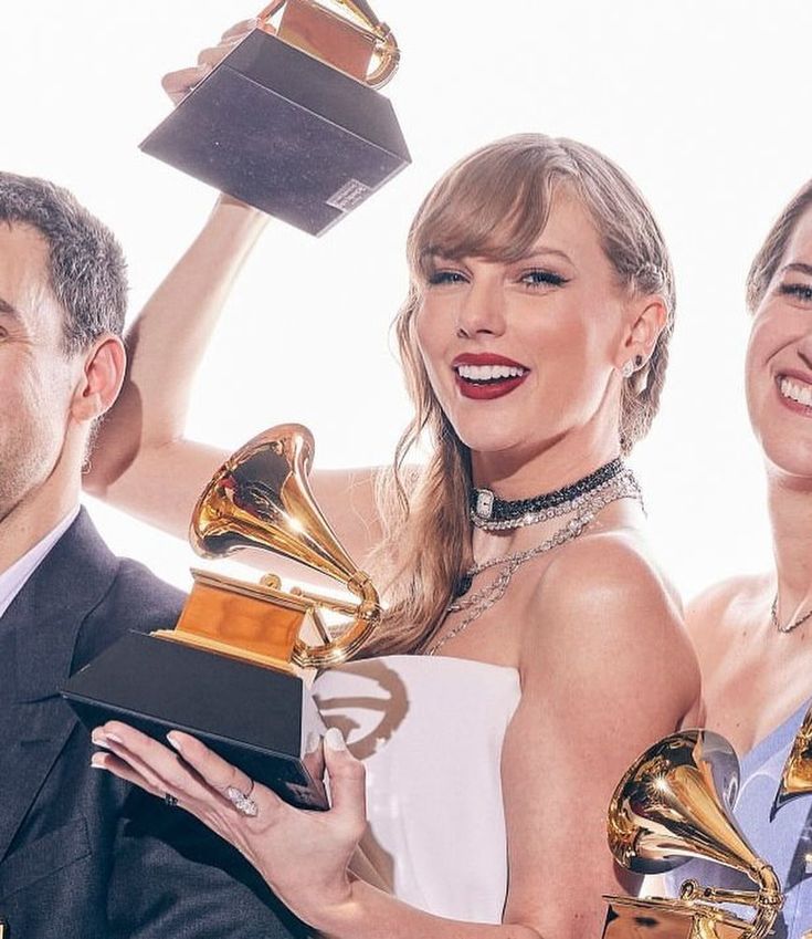 two women and one man are holding trophies