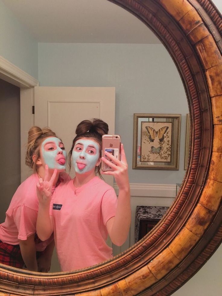 two people in pink shirts are looking into a mirror with their faces painted blue and white