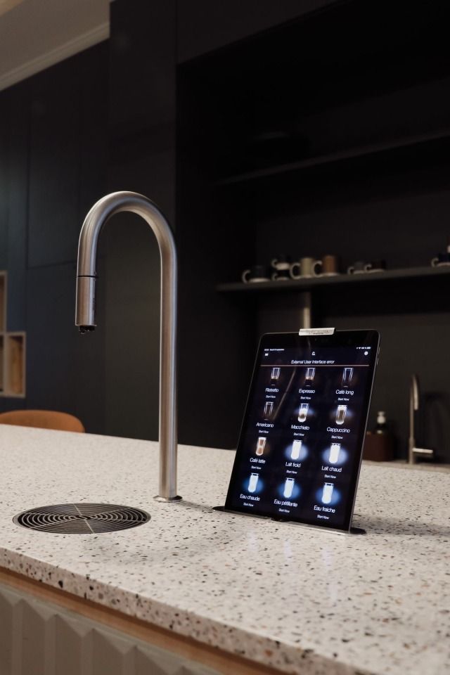 a tablet is sitting on the counter next to a faucet in a kitchen