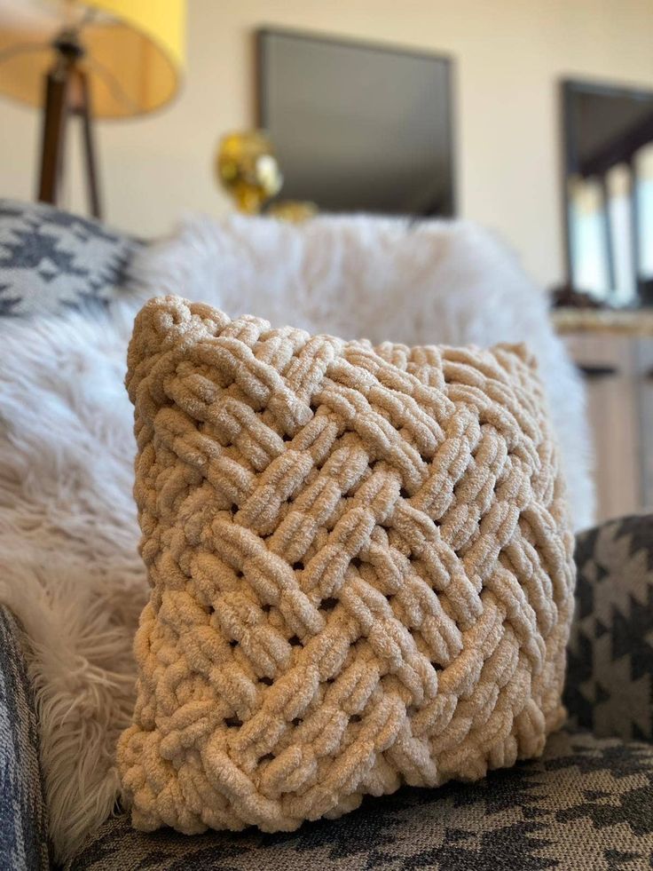 a close up of a pillow on a couch in a room with white fur and pillows