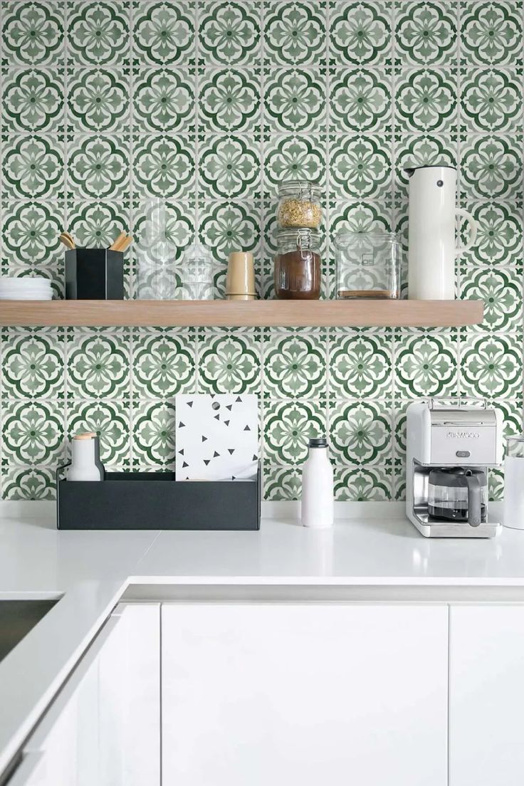 a kitchen with green and white wallpaper, shelves above the stove top and coffee maker on the counter