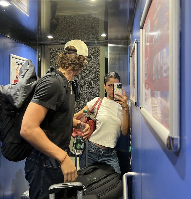 a man and woman standing next to each other in a room with luggage on the floor