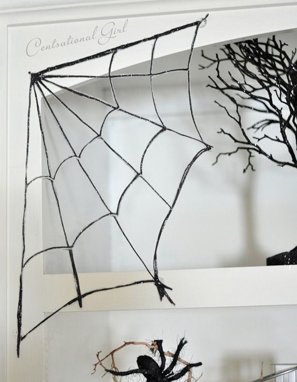 a spider web hanging from the side of a white wall next to a halloween tree