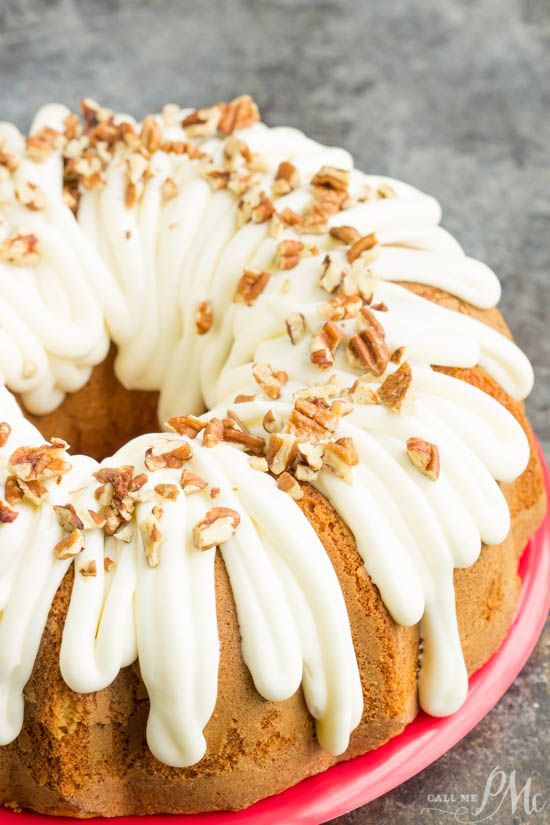 a bundt cake with white frosting and pecans on top sitting on a red plate