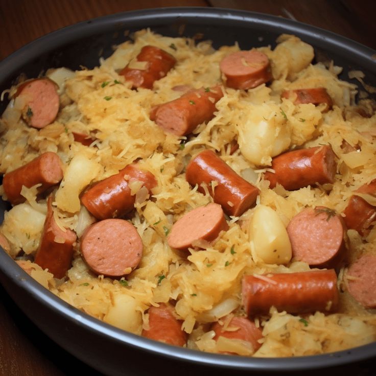 a pan filled with sausages, potatoes and sauerkraut on top of a wooden table