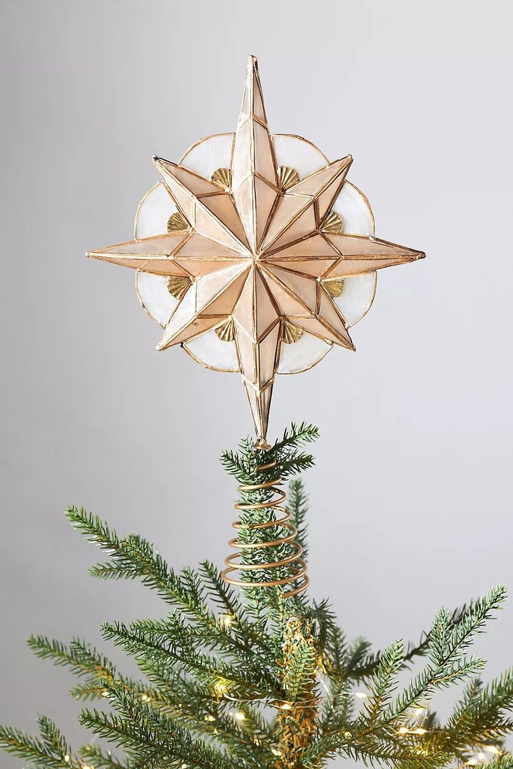 a star ornament hanging from the top of a christmas tree