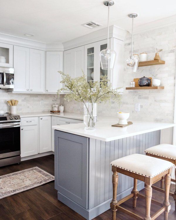 a kitchen with white cabinets and an island in the middle, surrounded by two stools