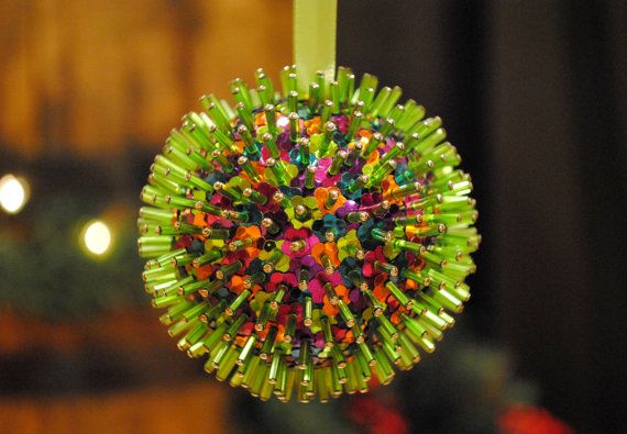 a green ornament hanging from a string with colorful beads in the shape of a ball