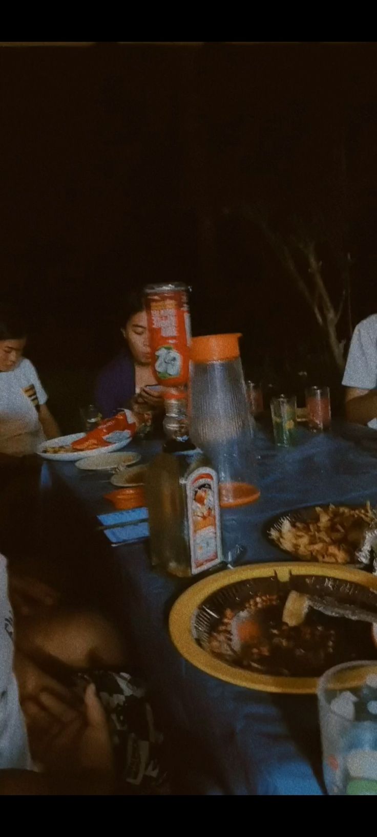 a group of people sitting around a table with food and drinks on top of it