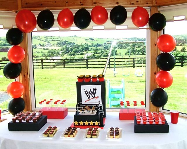 a table topped with desserts and balloons in front of a window