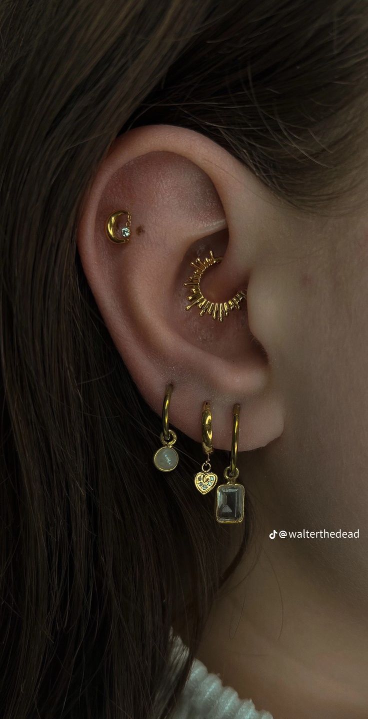 a close up of a person with ear piercings on their ears and wearing gold jewelry