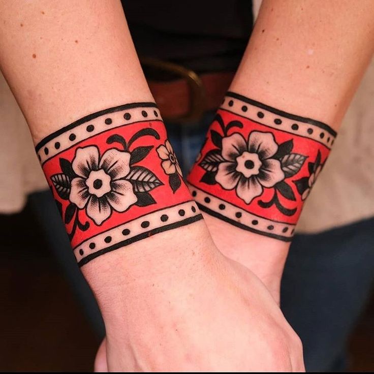 two wristbands decorated with flowers and leaves are shown in close up on both hands