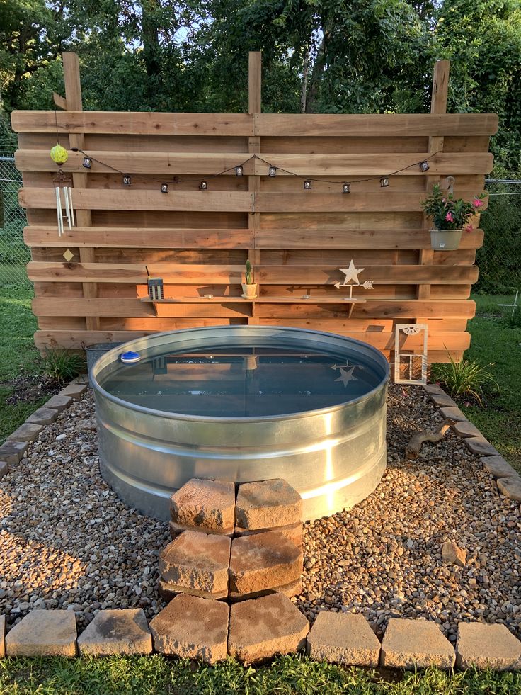 an outdoor hot tub in the middle of a yard with rocks and gravel around it