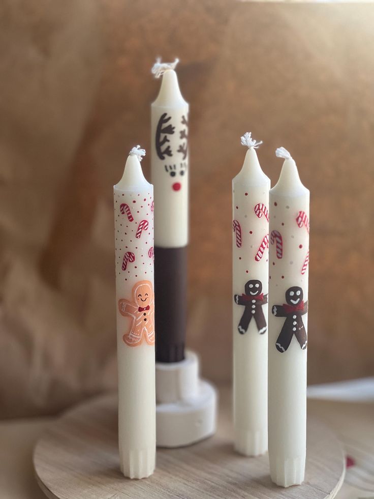 three white candles with black and red designs on them