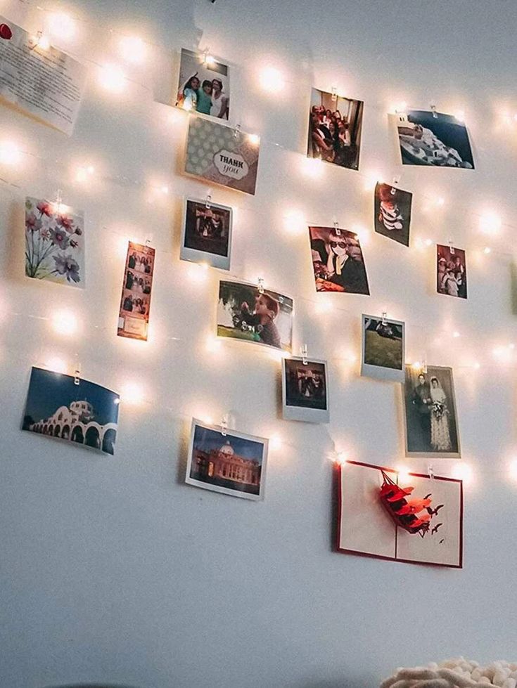 a bedroom with lights and pictures on the wall above it is lit up by string lights