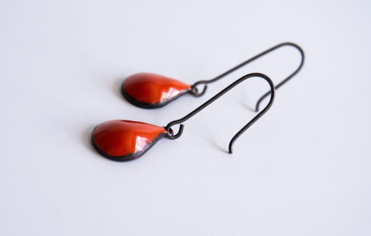 Discover the captivating allure of our red tear drop dangle earrings—a stunning addition that elevates your jewelry collection. These earrings feature a sleek raindrop-shaped design adorned with vibrant red-orange enamel, creating a unique and eye-catching aesthetic. The striking flame red hue beautifully contrasts against the blackened silver ear wires, making a distinctive statement. Crafted with durability in mind, these earrings not only boast exceptional visual appeal but also ensure long-l Red Teardrop Drop Earrings, Red Teardrop Earrings As A Gift, Red Nickel-free Teardrop Earrings, Nickel Free Red Drop Earrings, Nickel-free Red Teardrop Earrings, Nickel Free Red Teardrop Earrings, Handmade Red Teardrop Earrings, Modern Red Teardrop Jewelry, Red Enamel Drop Earrings