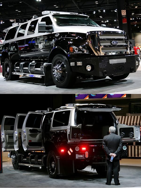 a man standing in front of a black and white truck with its lights on at an auto show