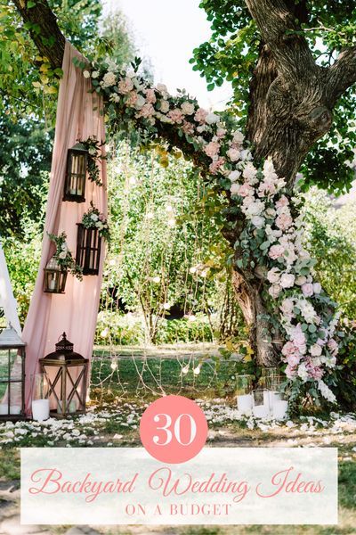 an outdoor wedding ceremony with flowers and lanterns on the ground, in front of a tree