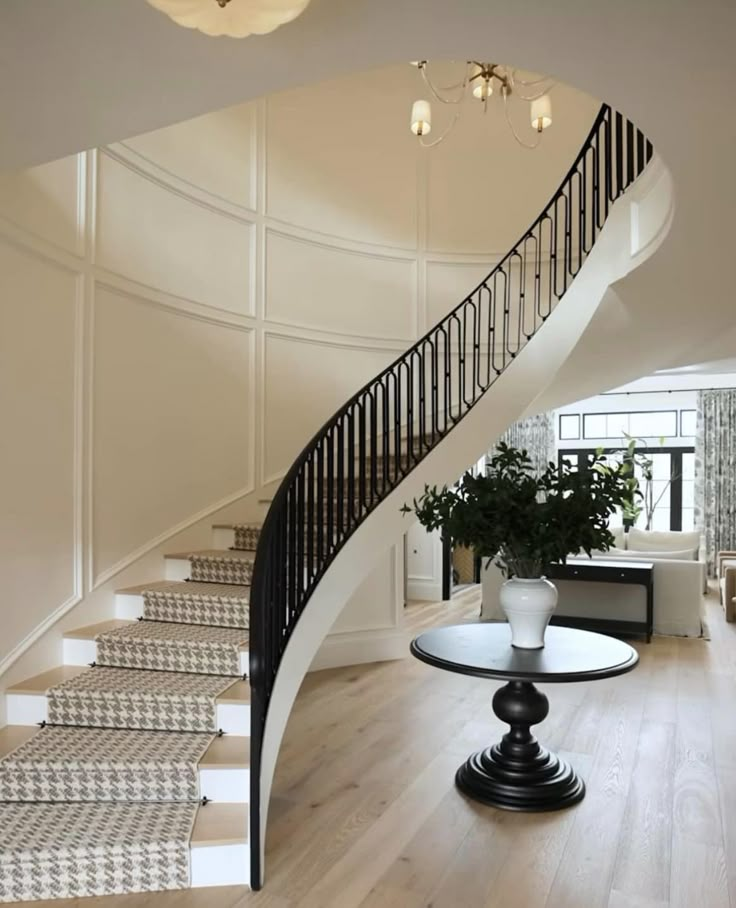 a white staircase with black handrail and glass table