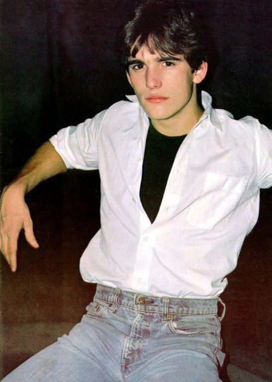 a young man in white shirt and black t - shirt posing for the camera with his hand on his hip