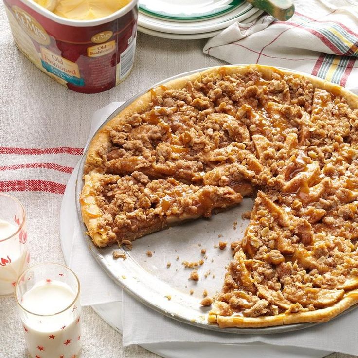 a pie sitting on top of a white plate next to a cup and glass of milk