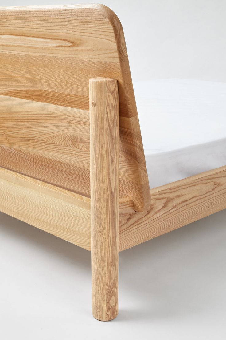 a wooden bed frame with white sheets on it