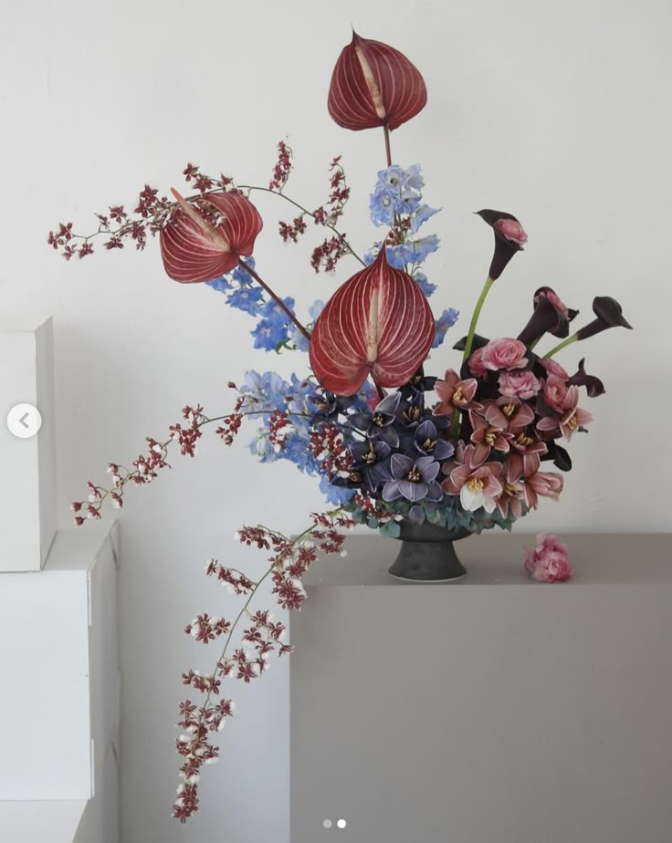 a vase filled with lots of flowers on top of a white table next to a wall