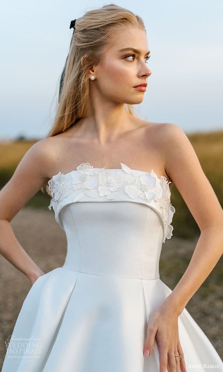 a woman in a white dress posing for the camera with her hands on her hips