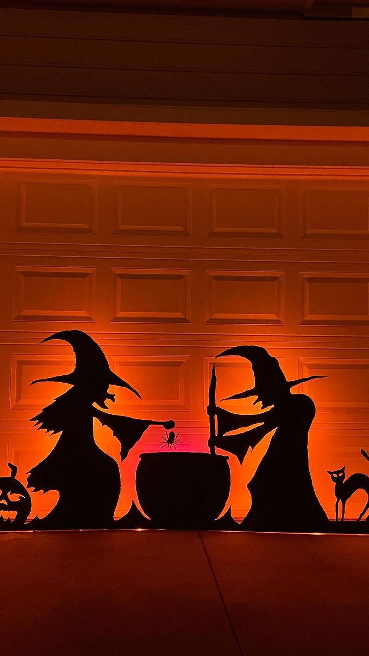 the silhouettes of witches and pumpkins are shown in front of a garage door