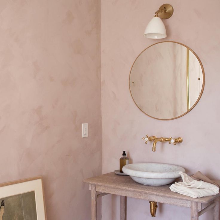 a bathroom with a sink, mirror and painting on the wall next to an old table