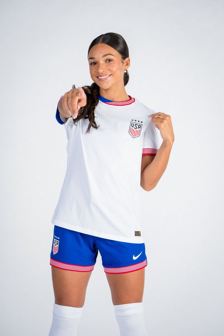 a female soccer player is posing for the camera with her arm in one hand and pointing to the side