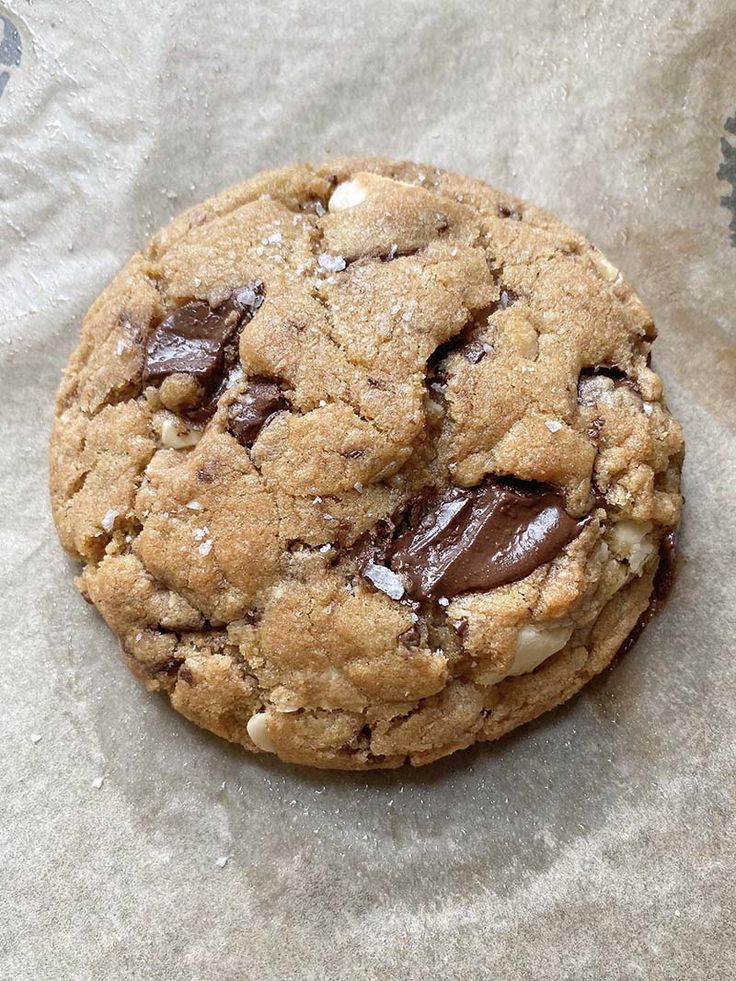 a chocolate chip cookie sitting on top of a piece of wax paper