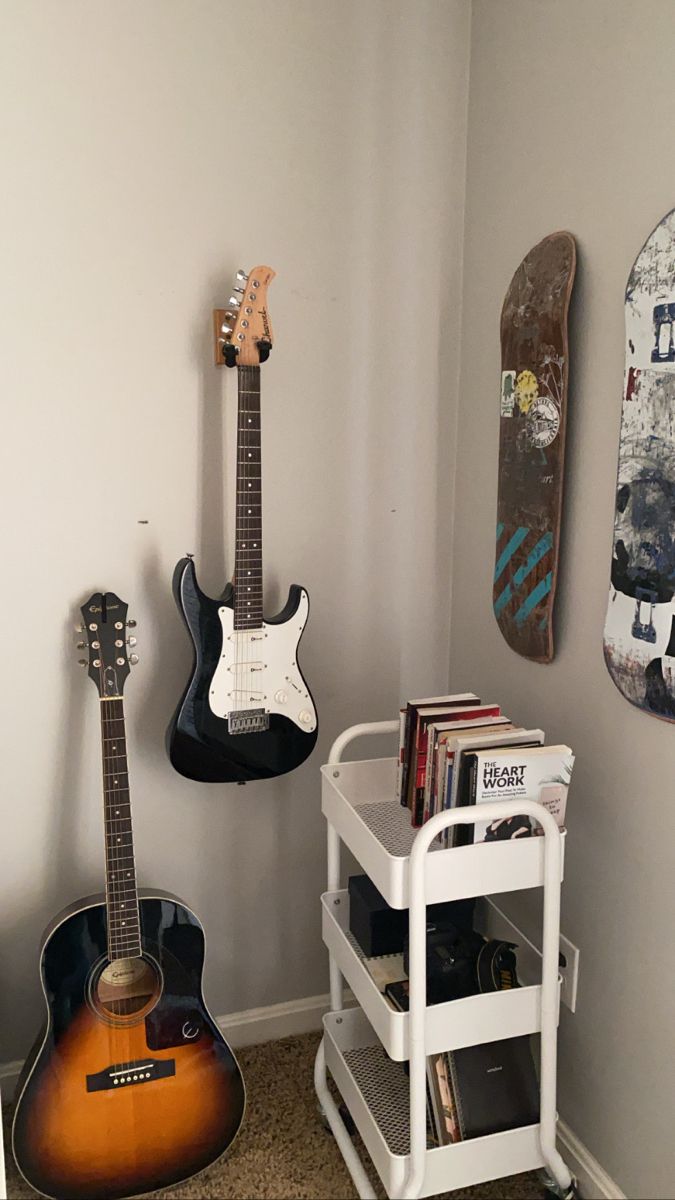 a room with two guitars, a skateboard and other items on the wall in it