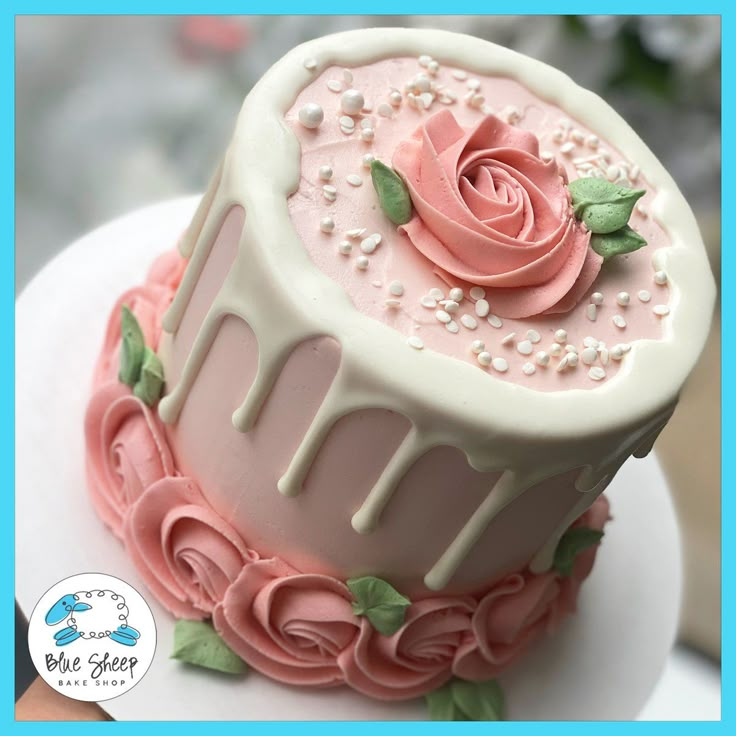 a pink and white cake with flowers on it's top is sitting on a plate