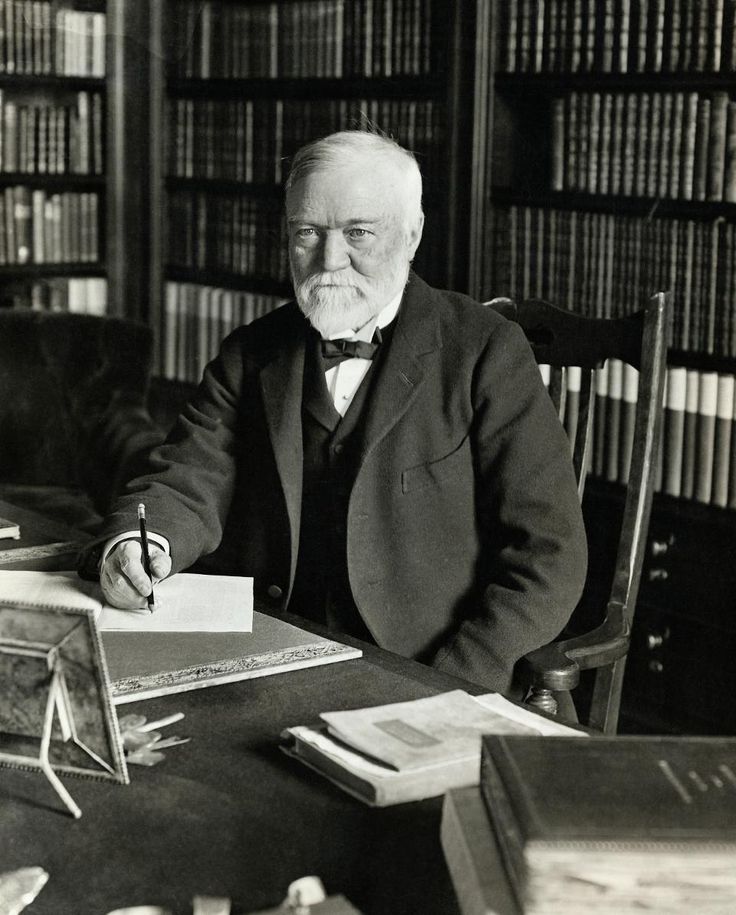 an old man sitting at a desk in front of books