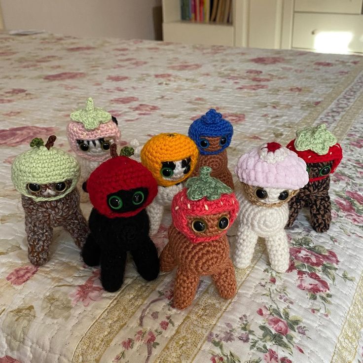 small crocheted stuffed animals sitting on top of a bed covered in floral bedspread