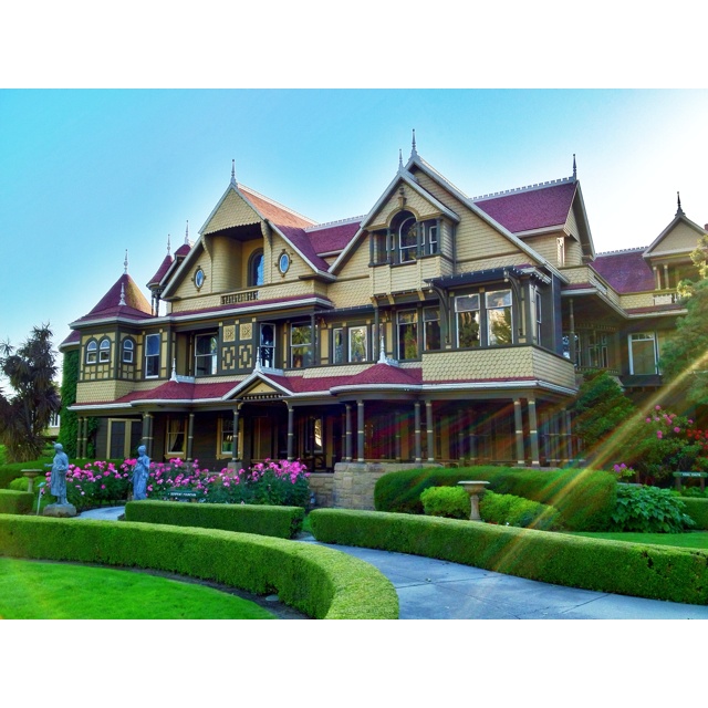 a large house with many windows and lots of greenery on the front lawn area