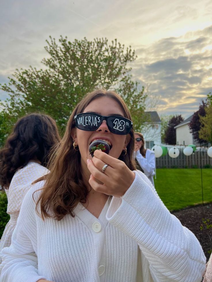 a woman wearing blindfolds and eating food in front of her eyes with other people behind her