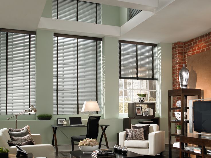 a living room filled with furniture and windows covered in shades of light green, white and brown