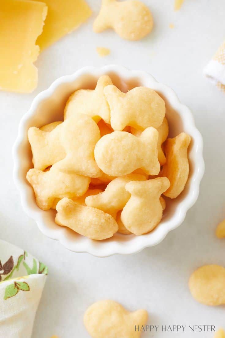 a bowl filled with heart shaped cookies on top of a white table next to slices of cheese